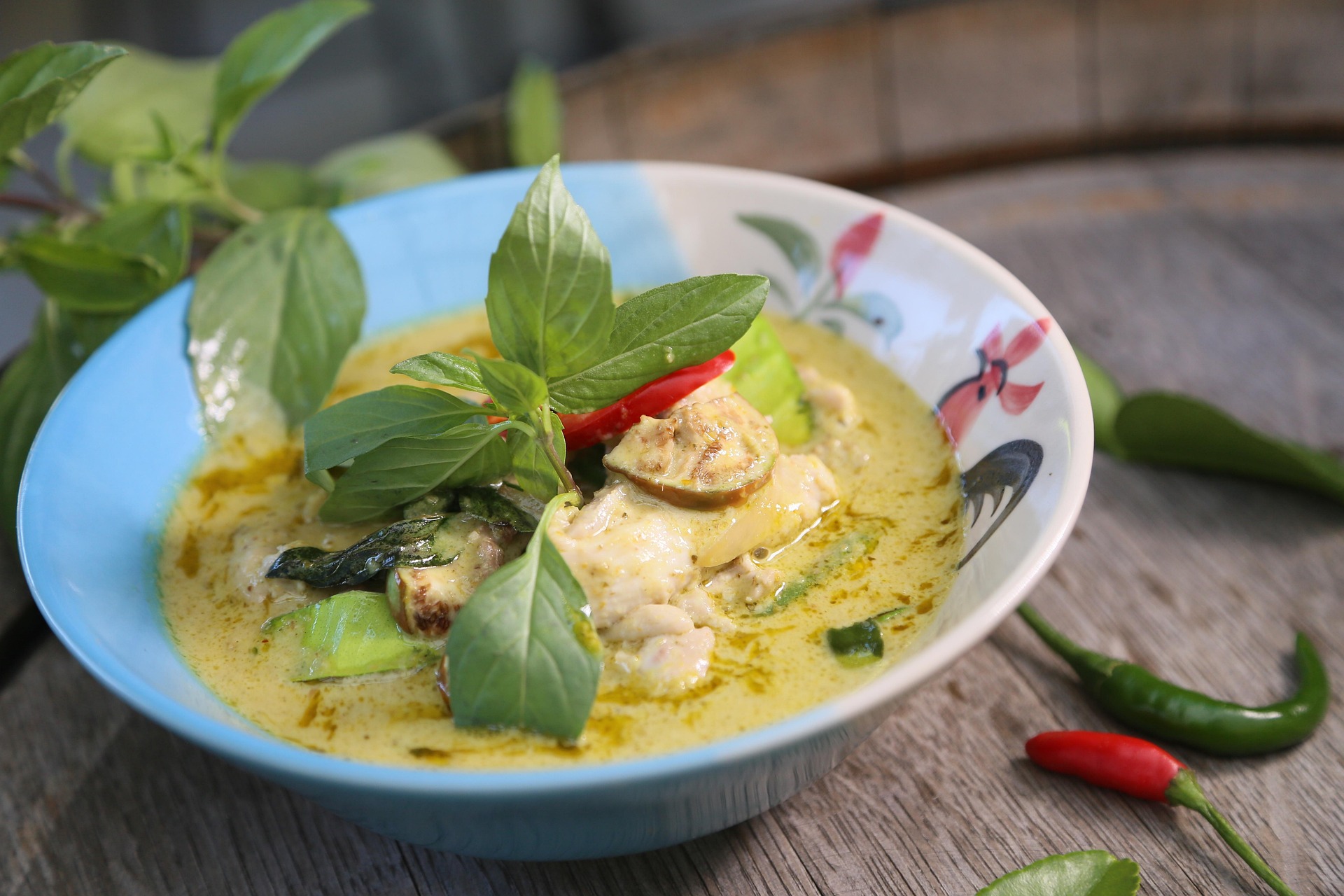 Thai green curry chicken in a bowl with fresh herbs