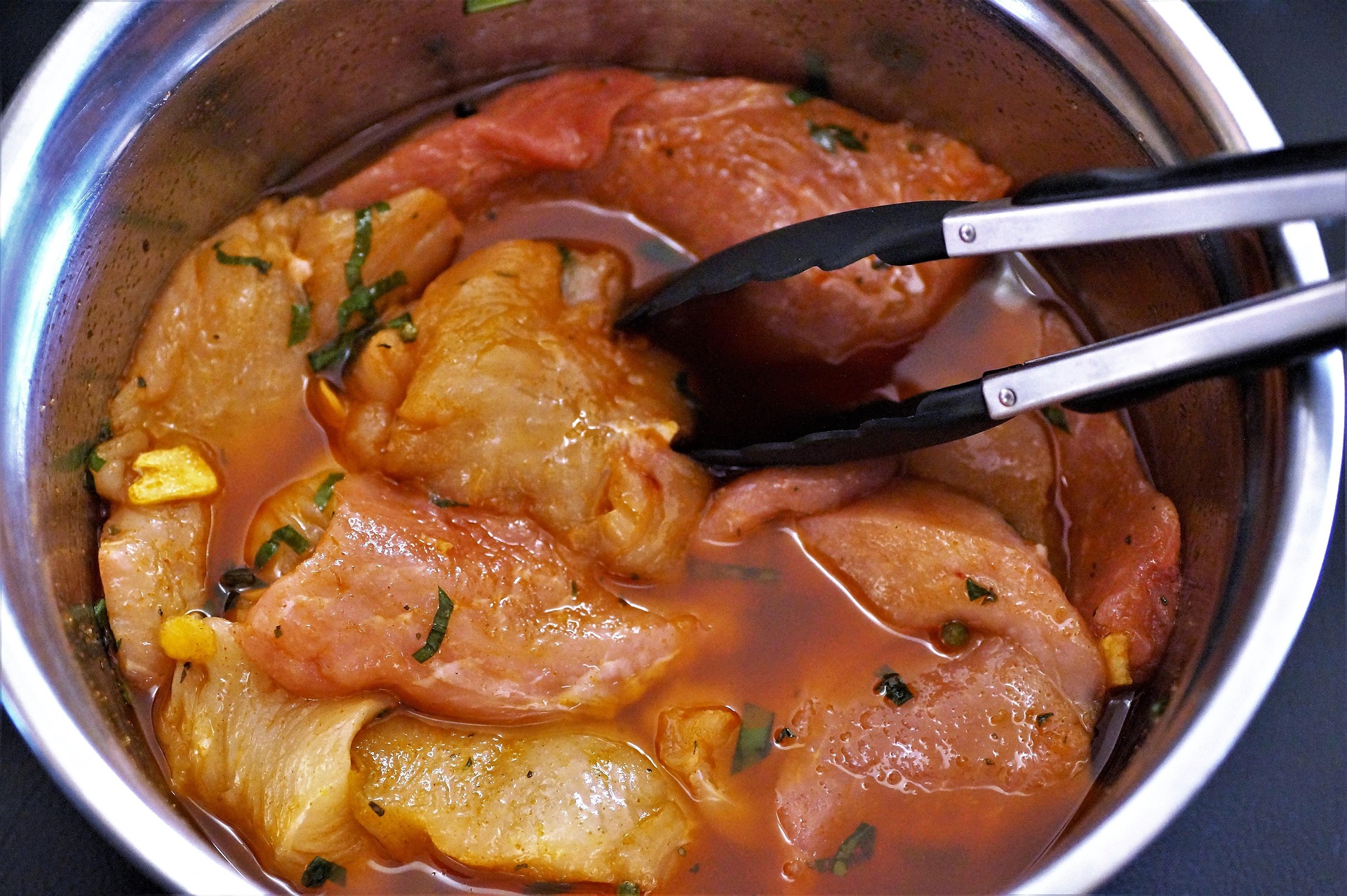Raw chicken thighs marinating in a tomato-herb sauce